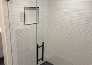 Modern design walk-in shower. Featuring white textured tile and dark floor for high-contrast look.