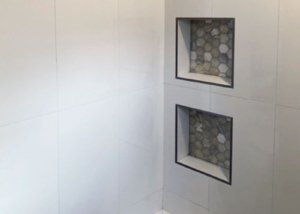 Gorgeous white tile shower with custom designed grey insets and seat.